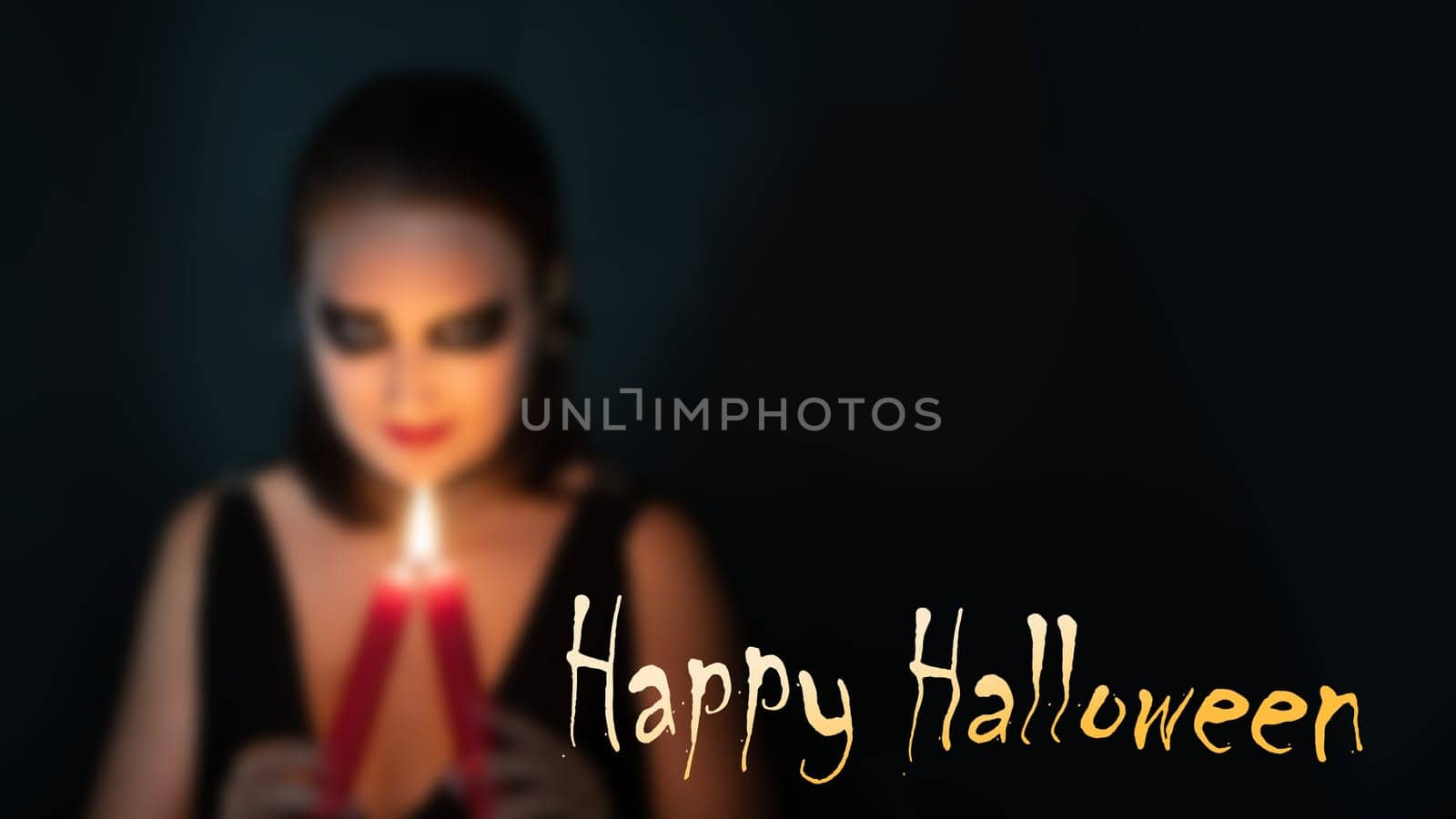 Blurred silhouette of woman in image of witch with burning candle in hands on black background with inscription Happy Halloween, concept of Halloween, copy space by Laguna781