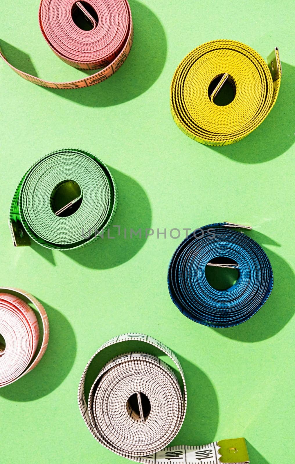 Dieting concept. colorful measuring tapes top view on bright green background, flat lay, pattern