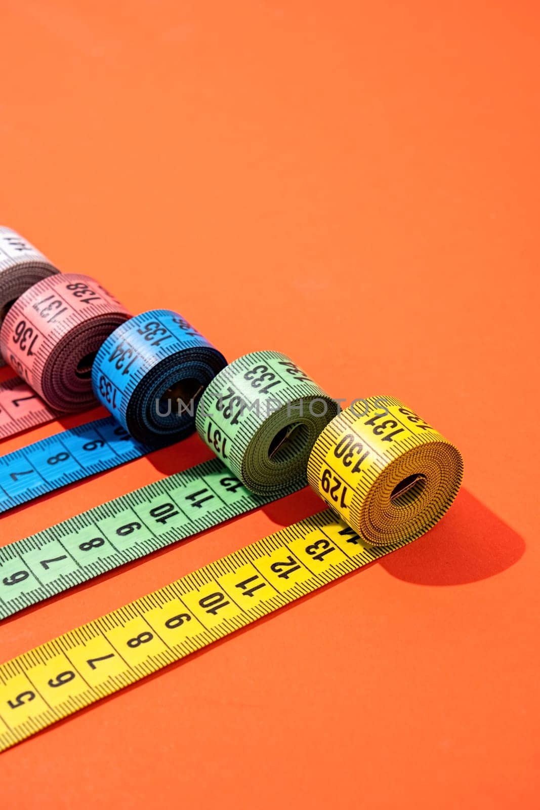 Dieting concept. colorful measuring tapes top view on bright red background, flat lay, pattern