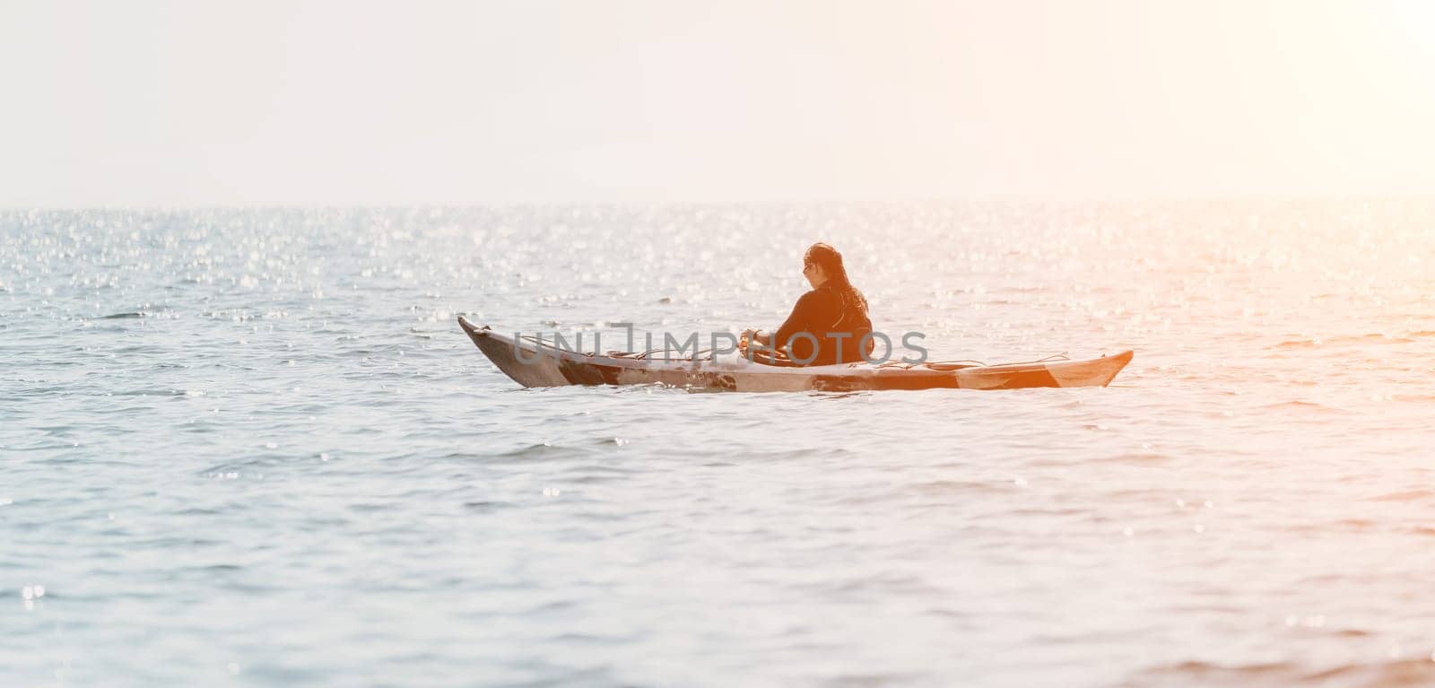 Happy smiling woman in kayak on ocean, paddling with wooden oar. Calm sea water and horizon in background