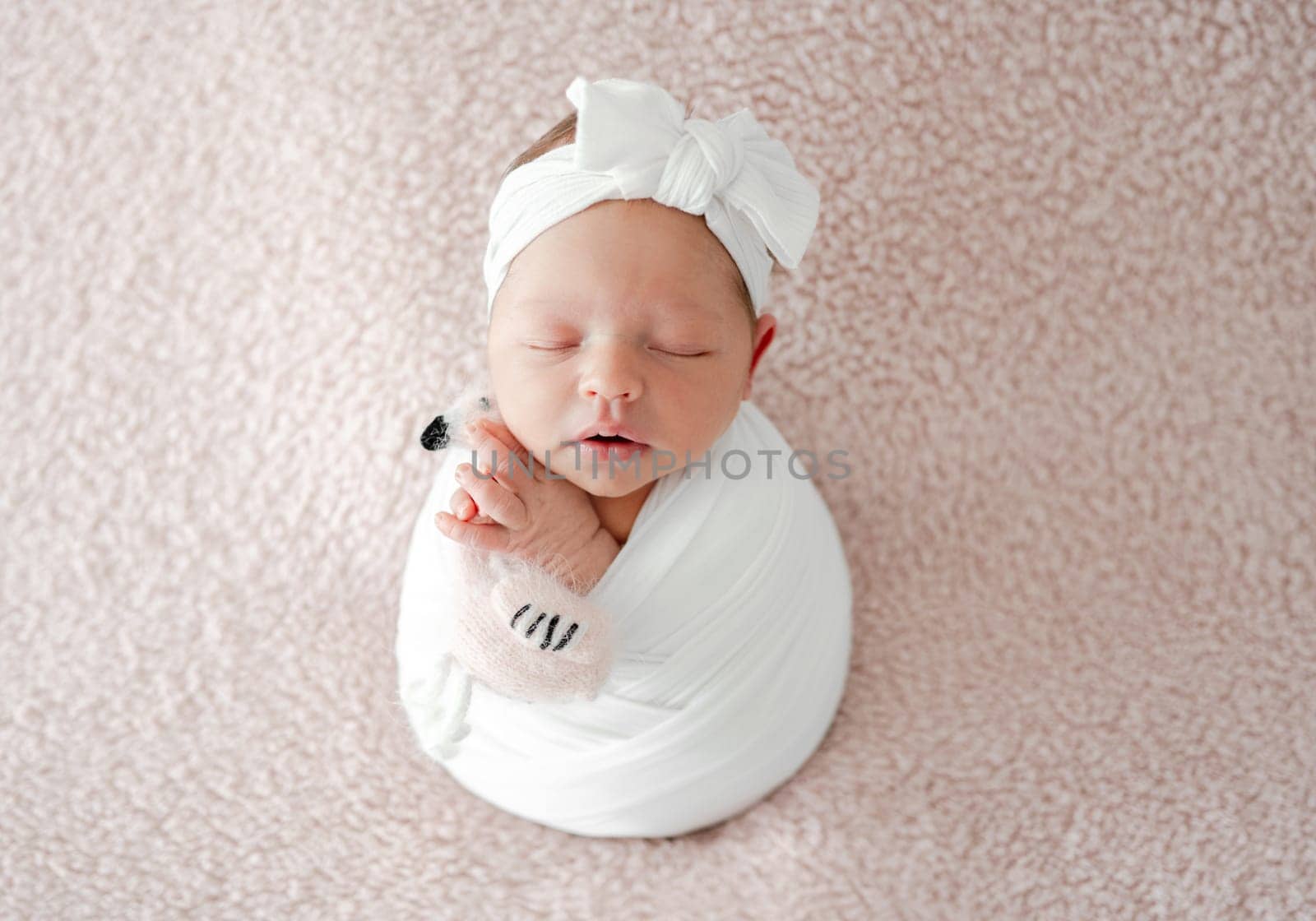 Sleeping Newborn Baby Wrapped In Swaddle Is A Studio Photo Of A Little Girl