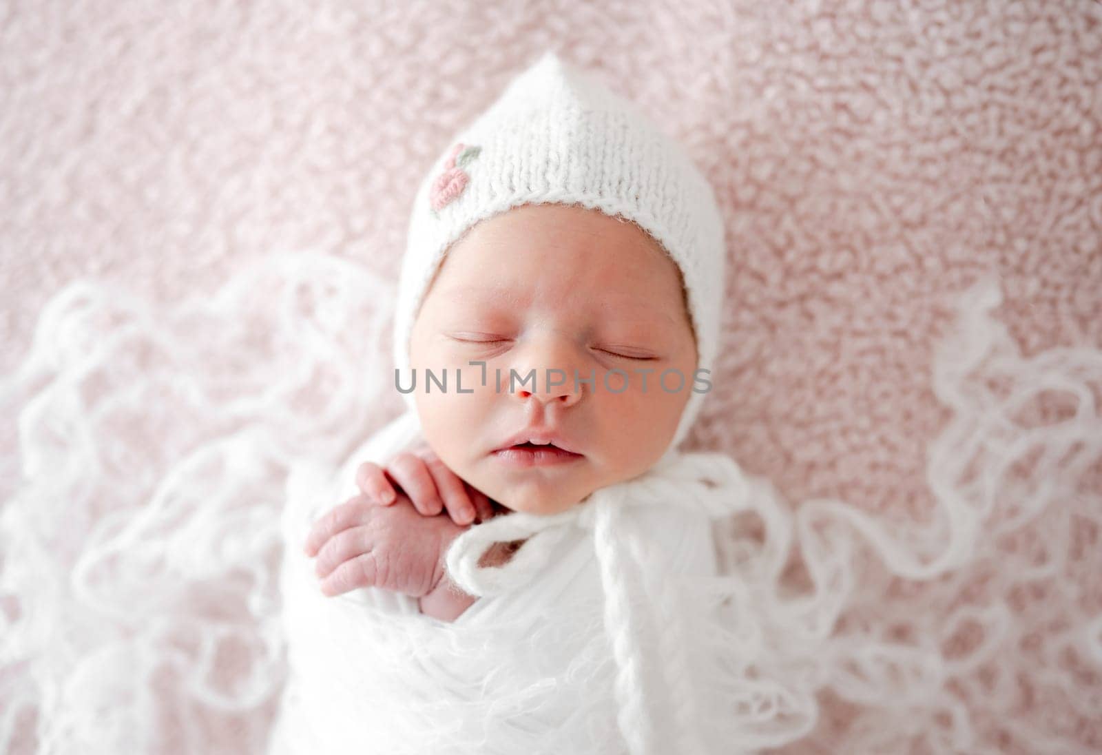 Sleeping Newborn Baby Wrapped In Swaddle Is A Studio Photo Of A Little Girl