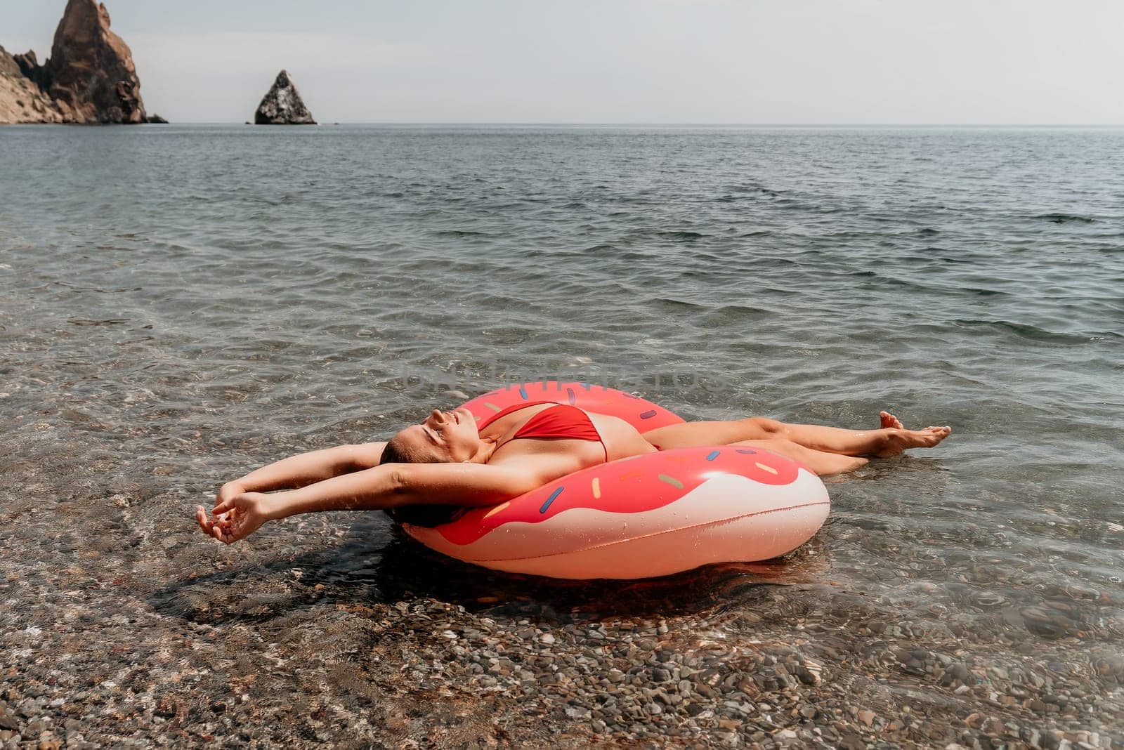 Summer Vacation Woman in hat floats on an inflatable donut mattress, a water toy swim ring. Unrecognizable young woman relaxing and enjoying family summer travel holidays vacation on the sea