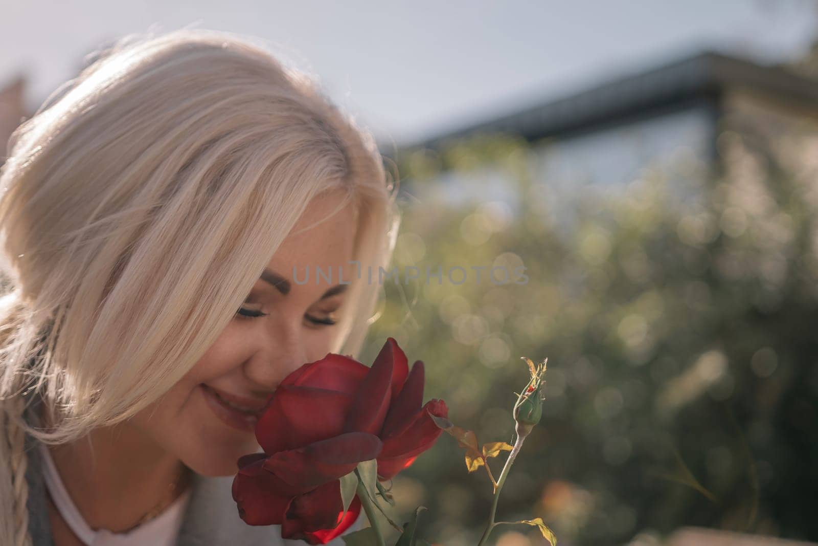 A woman is smelling a red rose. Concept of happiness and contentment, as the woman is enjoying the scent of the flower