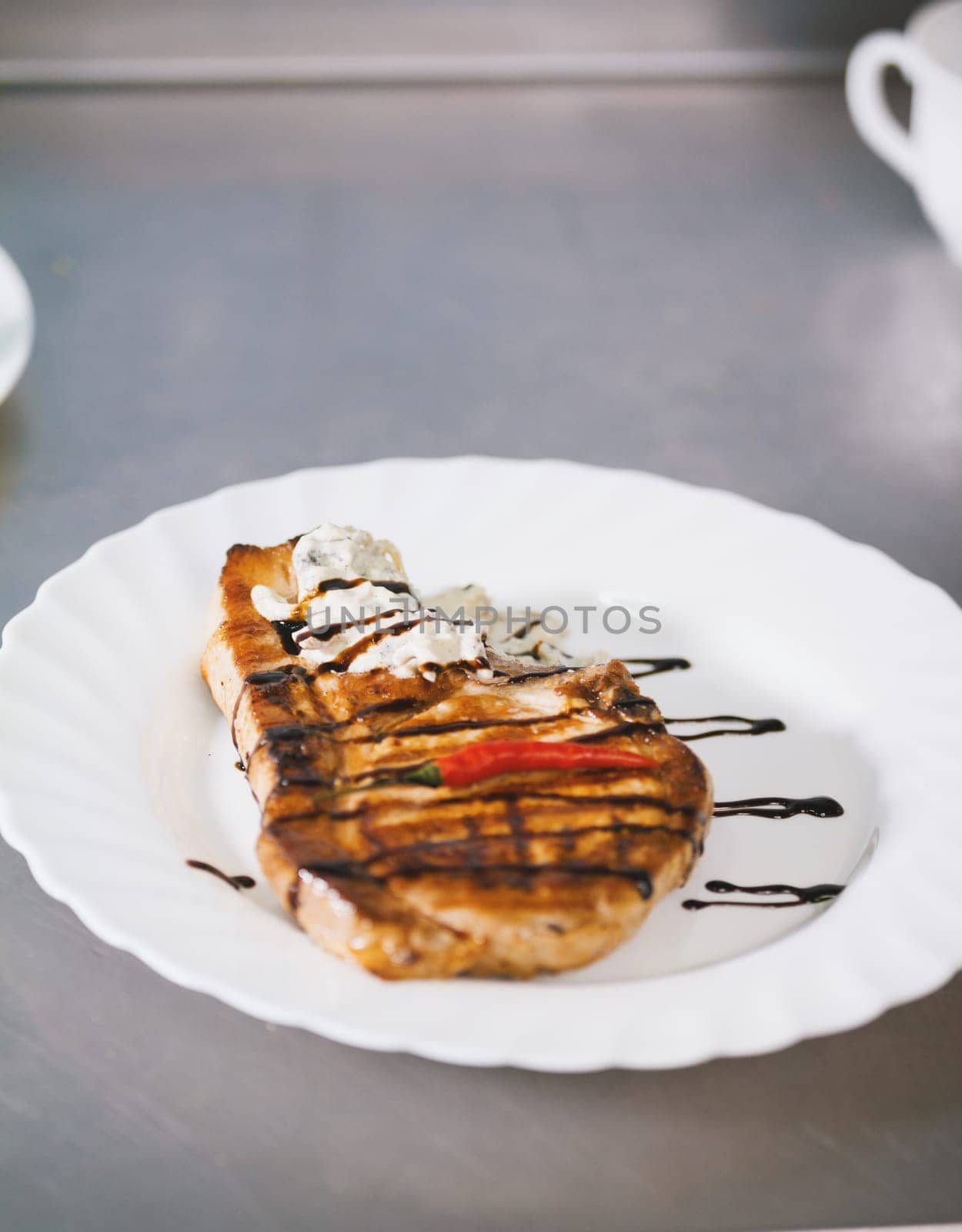 Steak on the plate with cream and chocolate sauce and pepper, close up