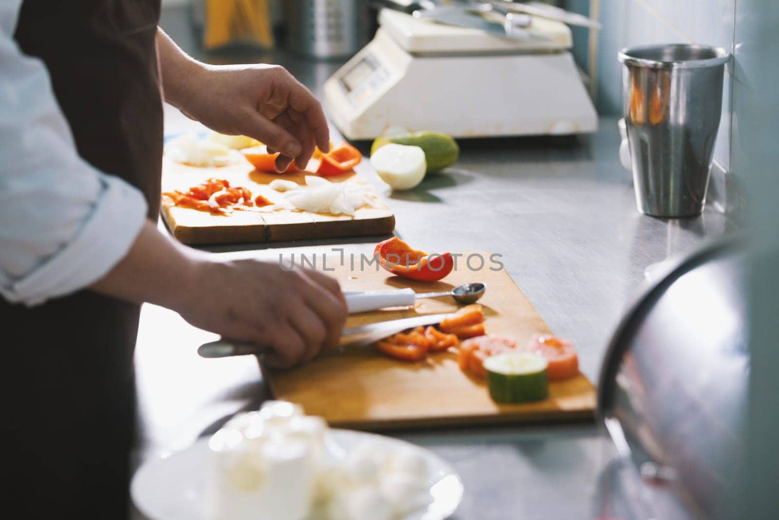 Chef chops vegetables for salad in commercial kitchen close-up