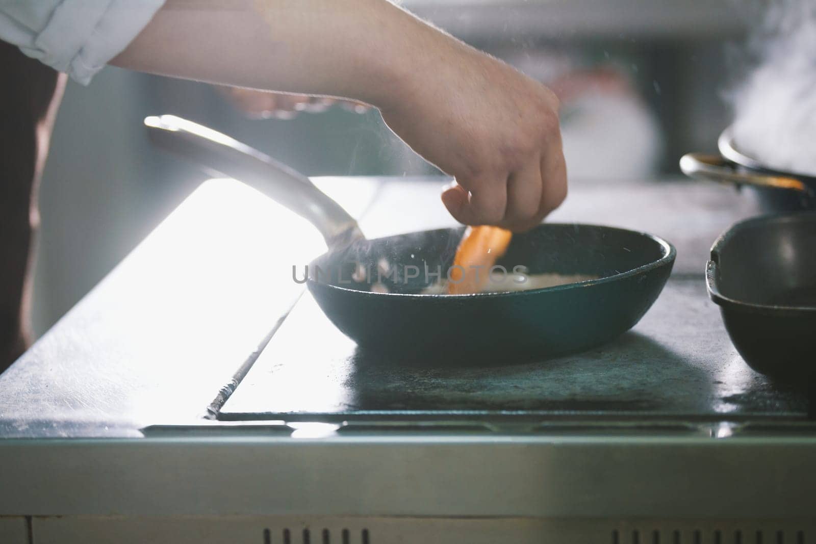 chef is frying meat and vegetables in a pan close-up