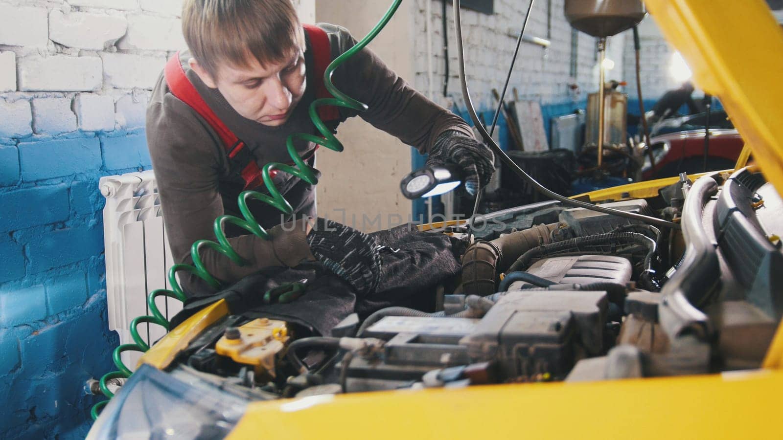 Mechanic unscrews detail of car in hood - automobile service repairing, close up view