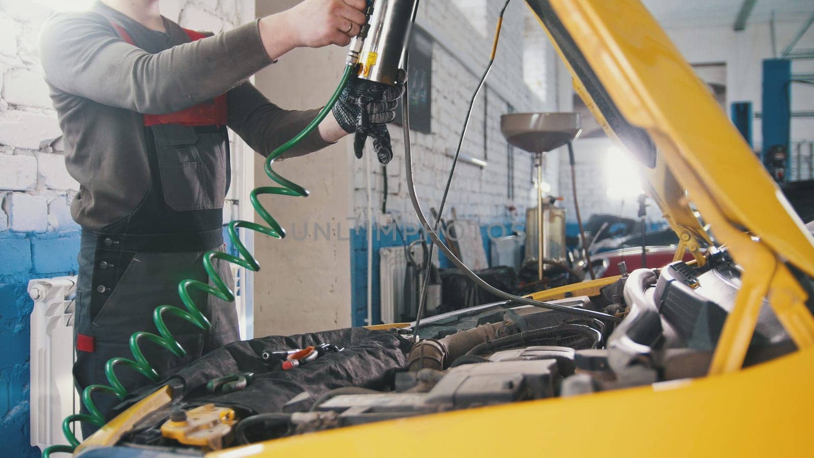 A mechanic checks the electrical in the hood of the car- repairing in engine compartment, close up