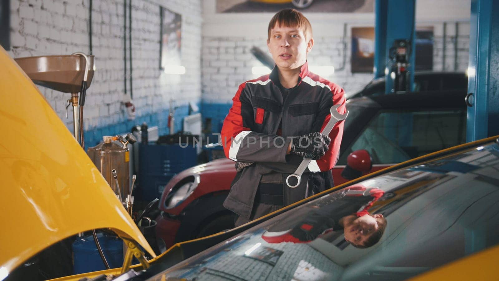 Portrait of a young car mechanic in overalls in a car workshop, portrait