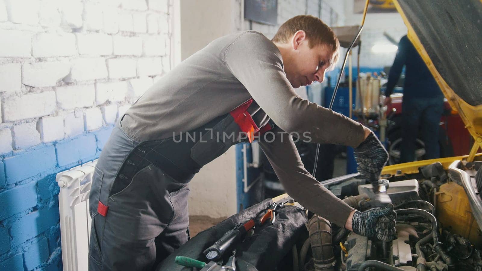 Mechanic in car repairing service - diagnostics in engine compartment, close up