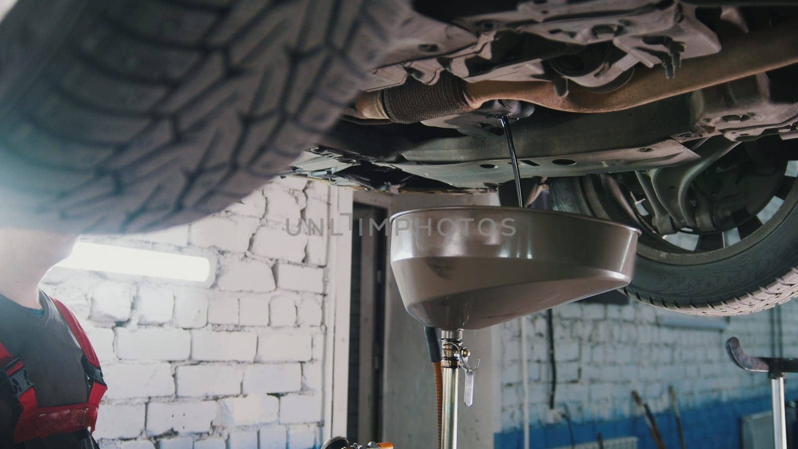 Engine oil under bottom of the car in garage workshop, close up view