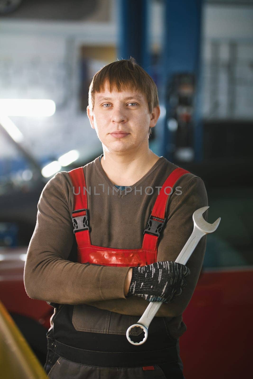 Portrait of a young car mechanic in a car workshop, vertical