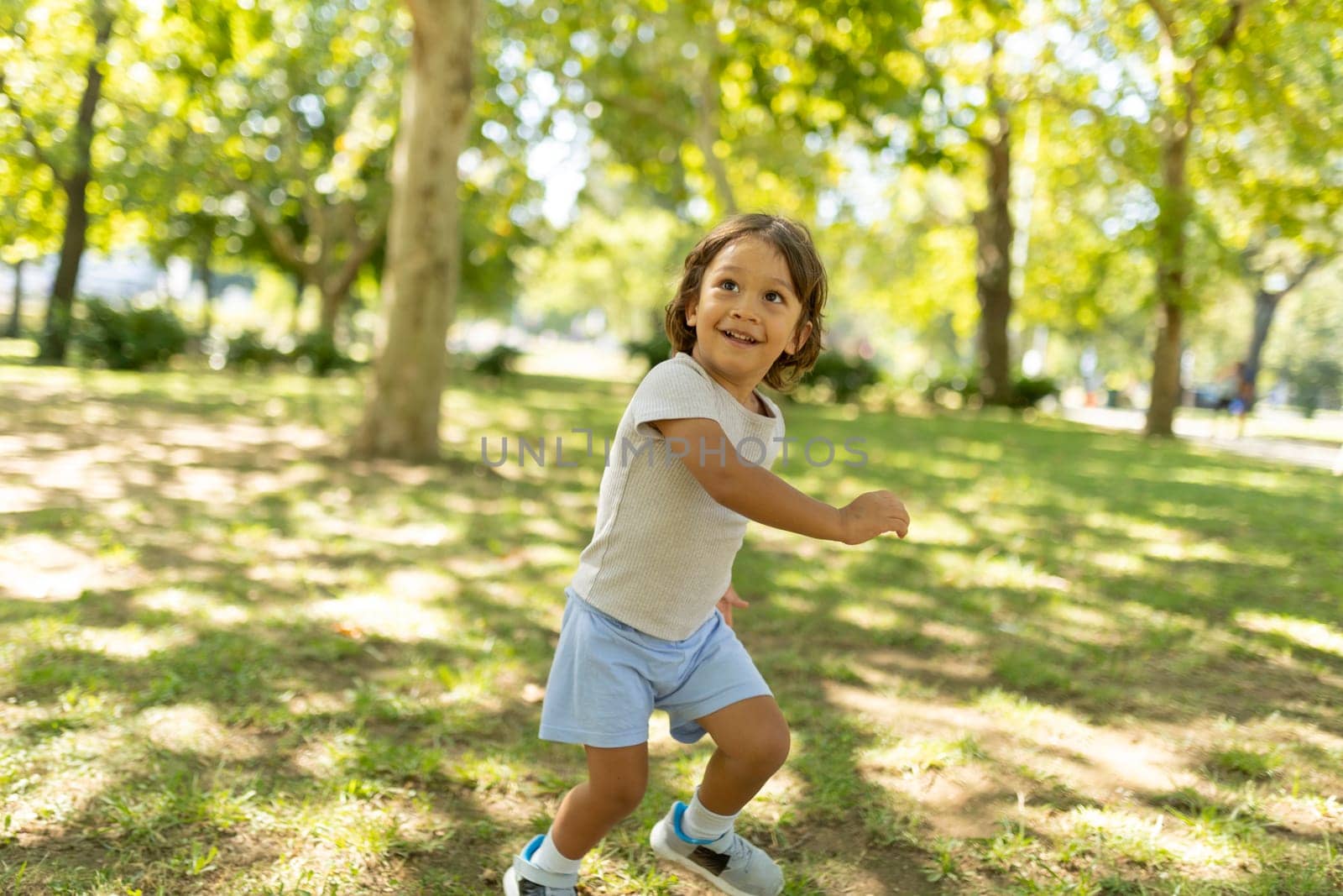 Young boy joyfully running through a park on a sunny summer day