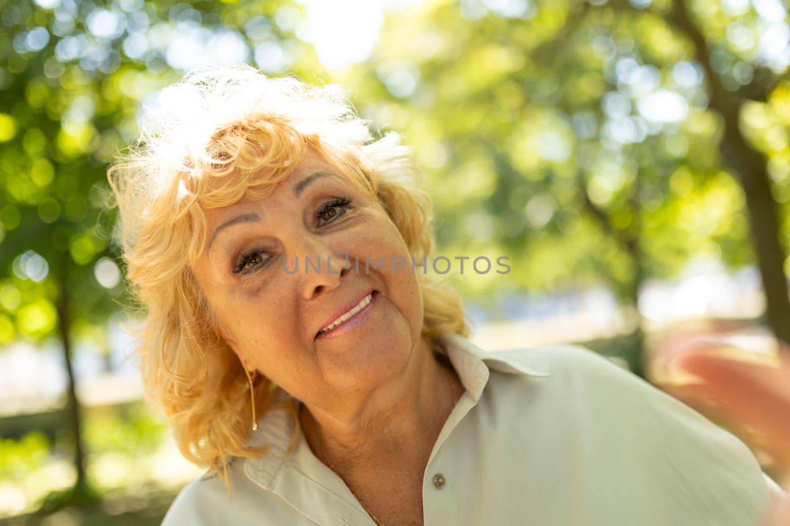 Happy mature woman with blonde hair enjoying sunny day in nature
