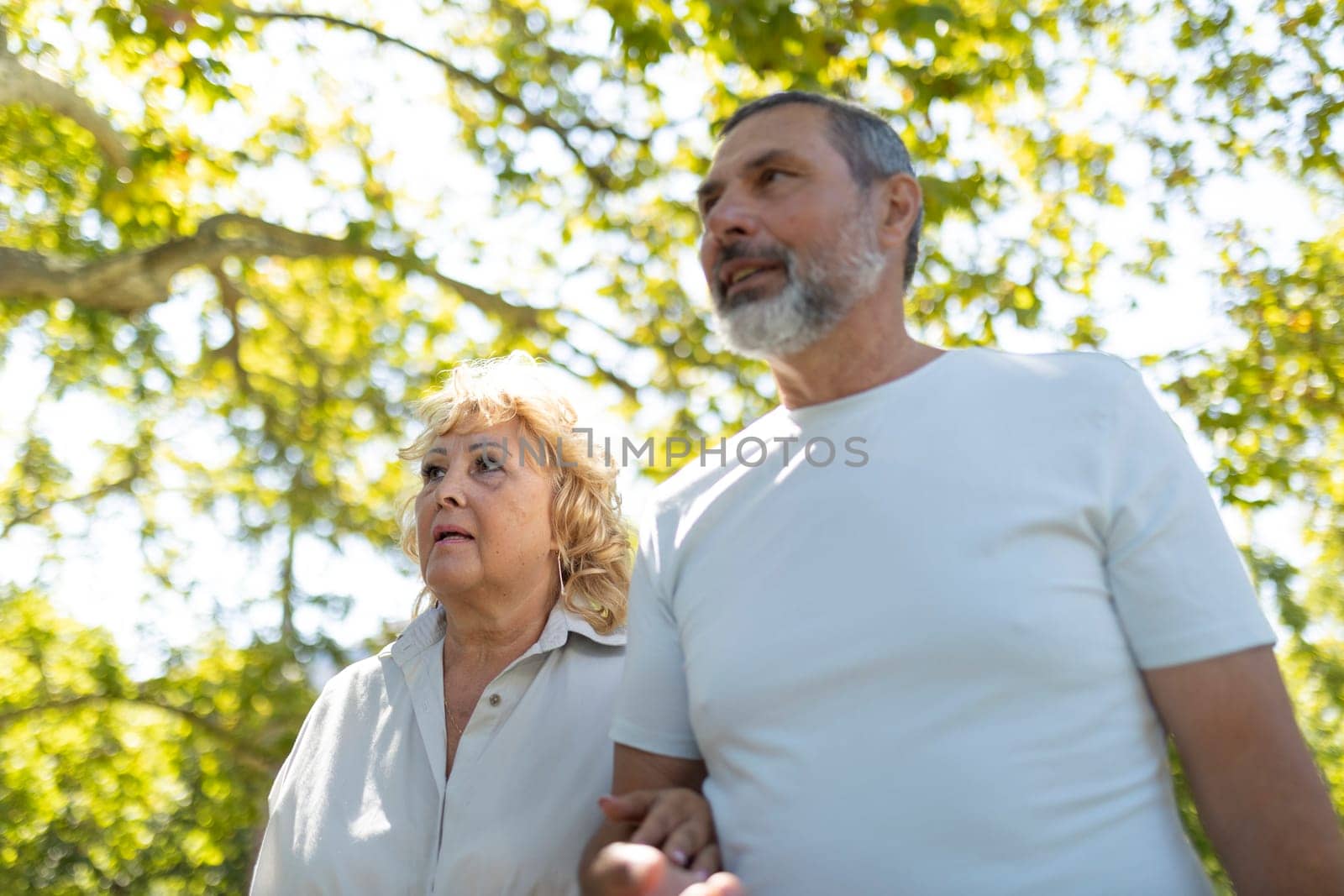 Senior couple is enjoying their retirement by taking a peaceful walk in the park on a sunny day