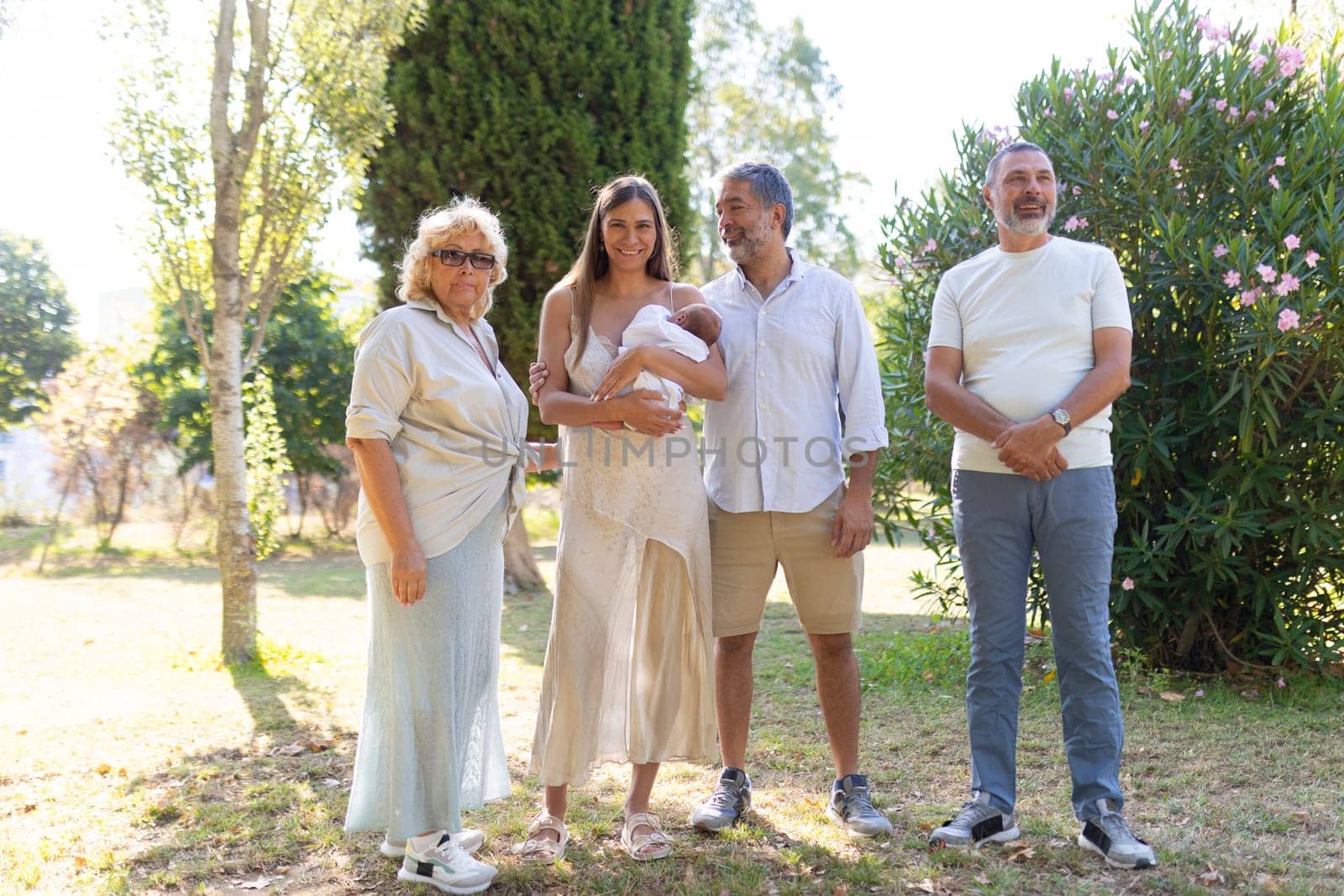 Happy family is standing together in the park, celebrating the arrival of their newborn baby