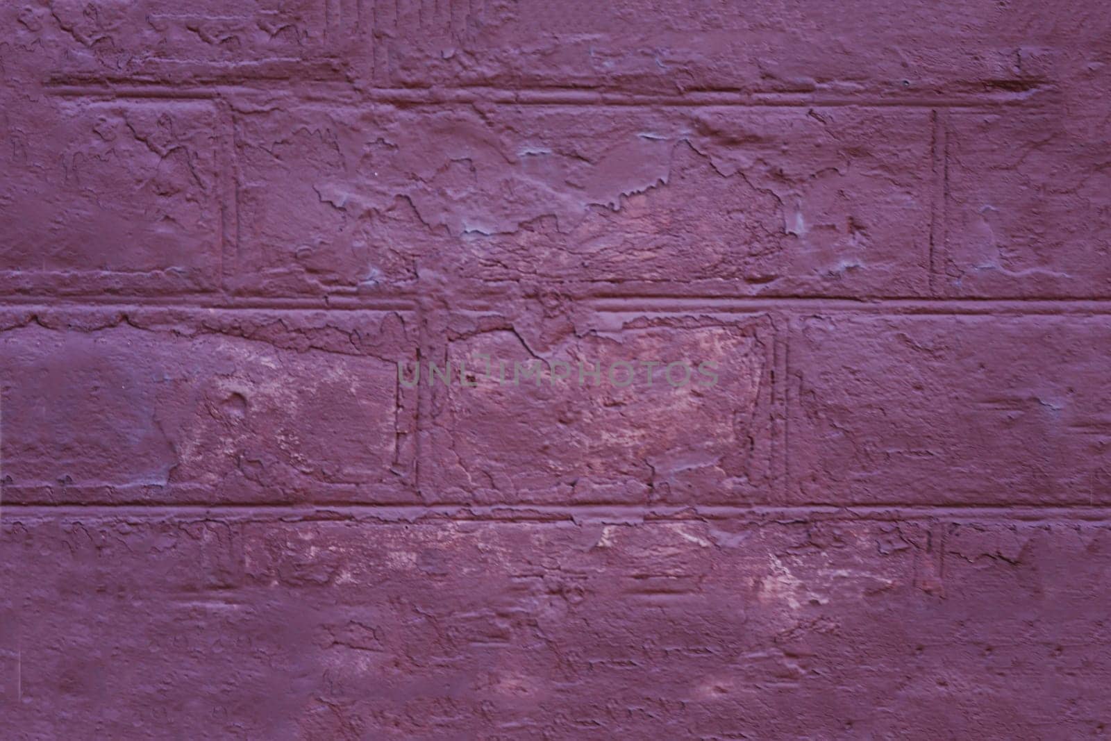 Fragment of the facade of a brick wall of an old purple building.