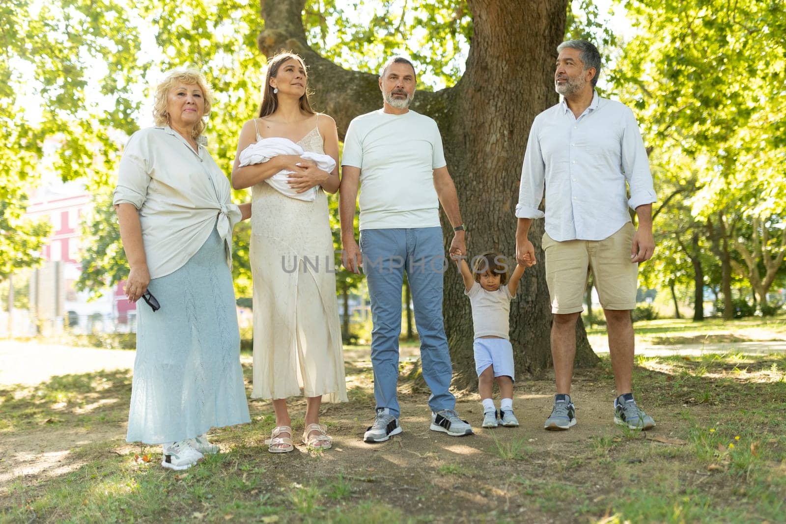 Happy family is posing for a photo while standing together in a park