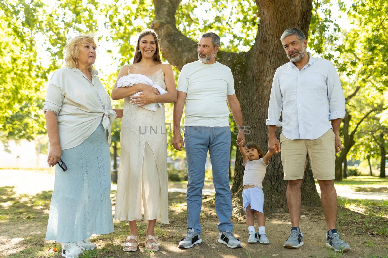 Family is gathering in a park, celebrating the arrival of a newborn baby