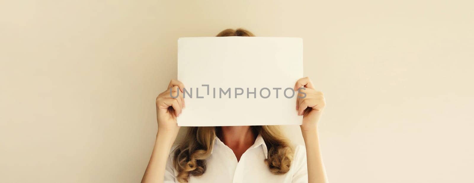 Woman showing and holding white blank sheet of paper document for advertising text blank copy space on studio background