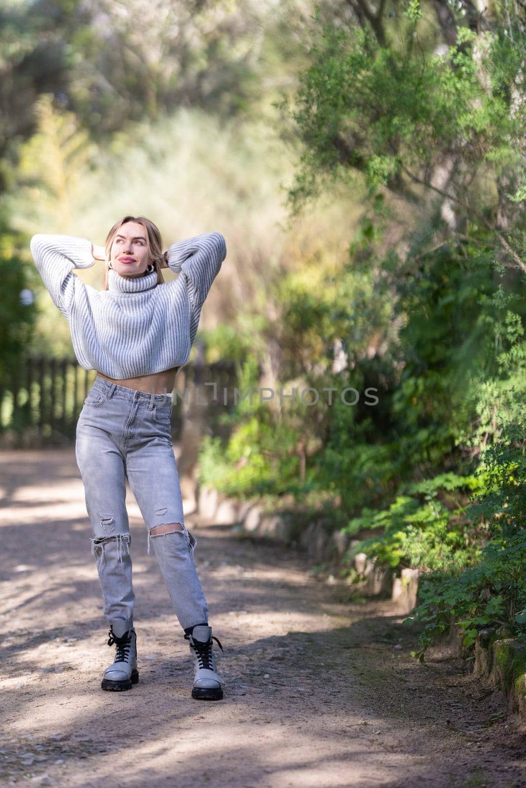 Young woman is taking a break from her hike, stretching and enjoying the fresh air