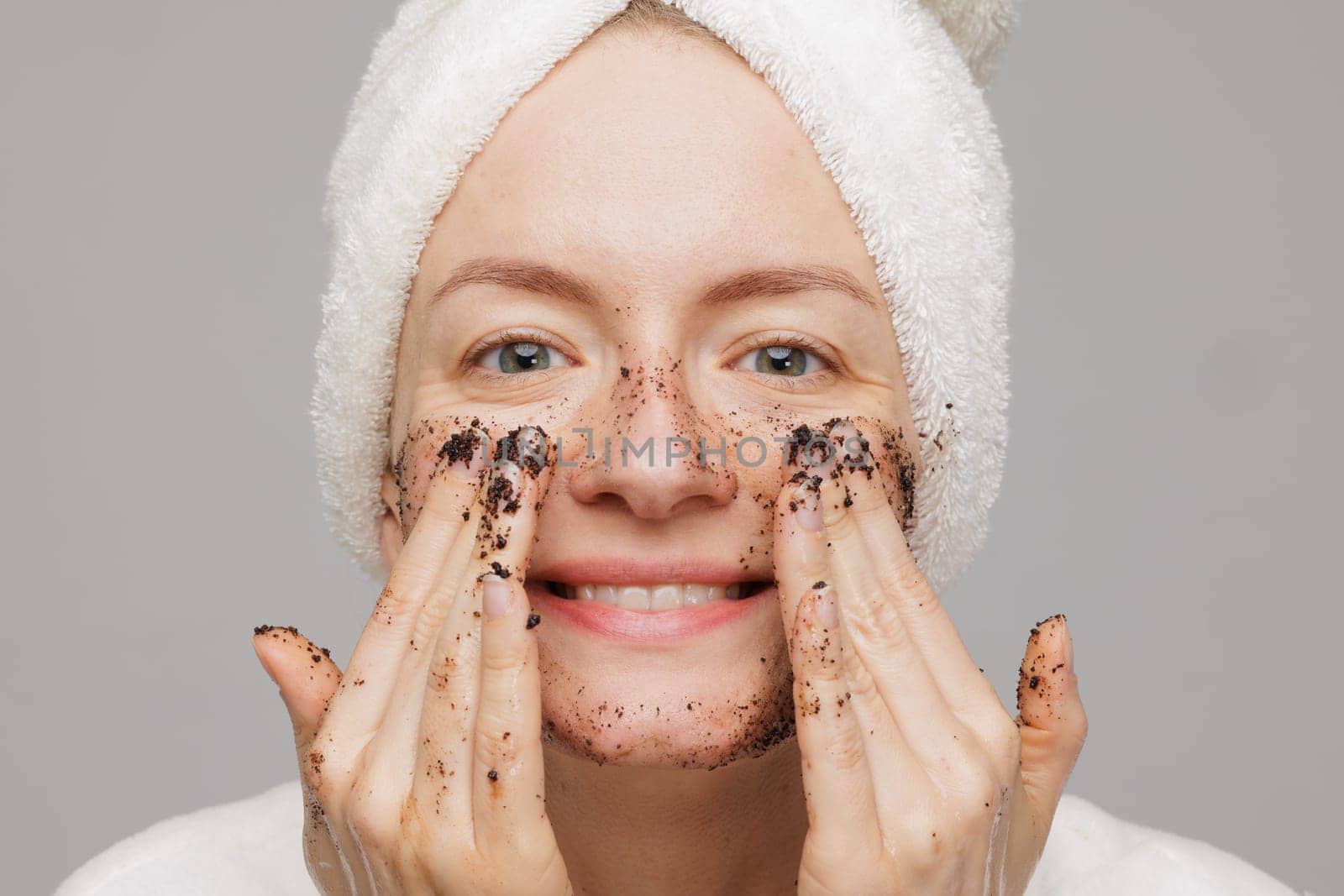Woman enjoying facial skin care, applying black coffee face scrub, concept of rejuvenation and facial skin care