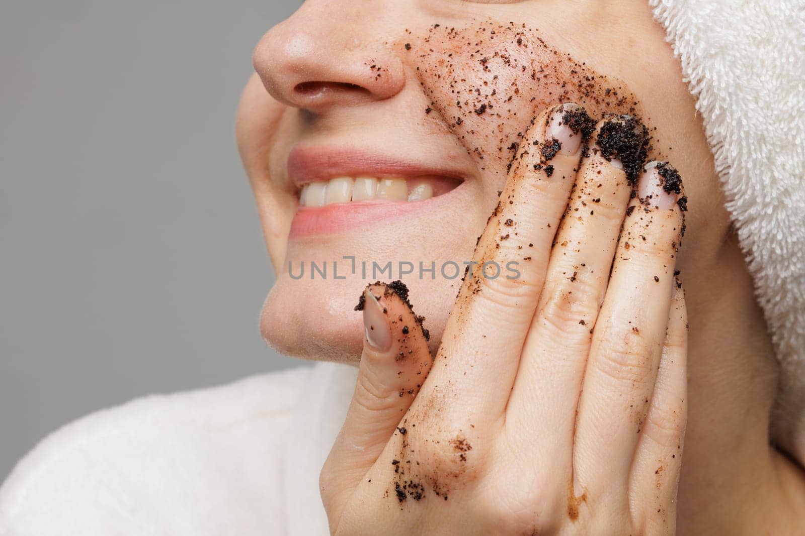 Woman enjoying facial skin care, applying black coffee face scrub, concept of rejuvenation and facial skin care