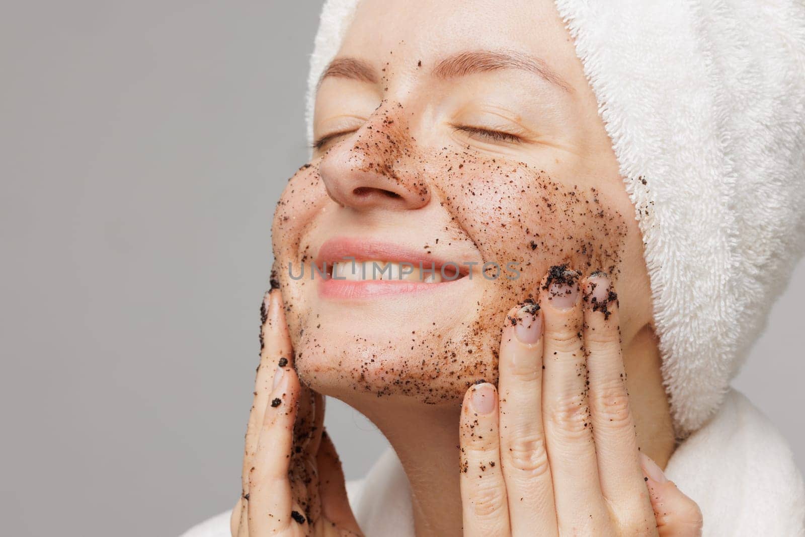 Woman enjoying facial skin care, applying black coffee face scrub, concept of rejuvenation and facial skin care