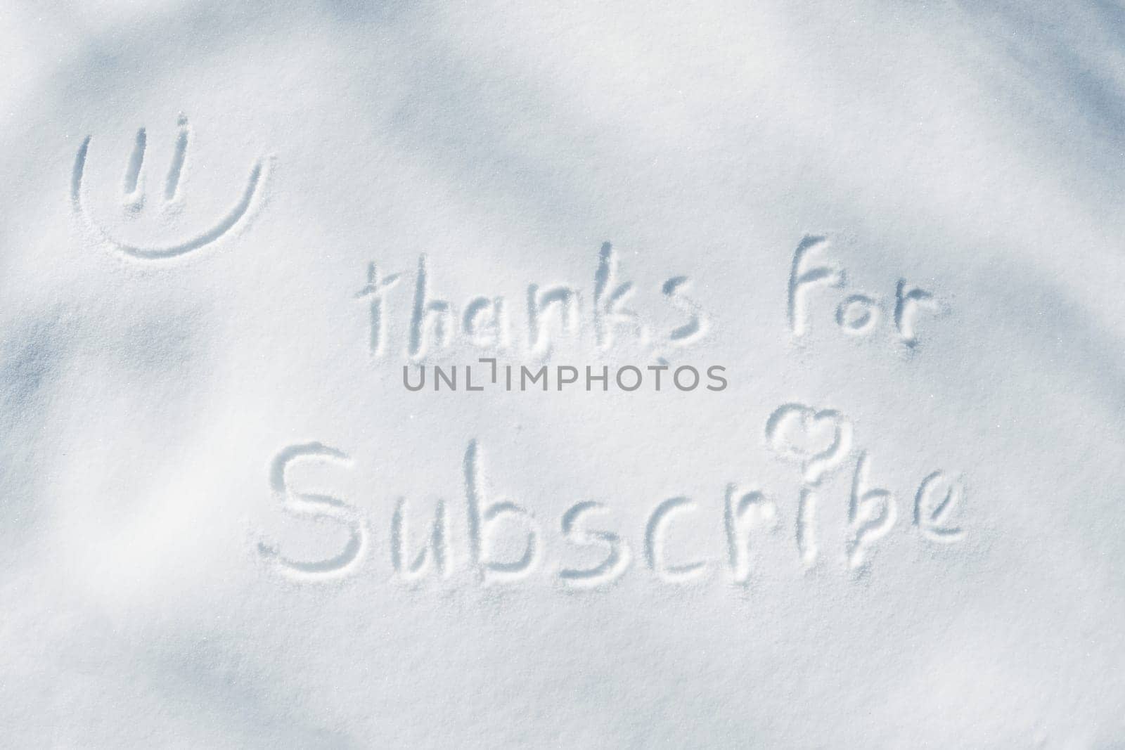The inscription THANKS FOR SUBSCRIBE with a heart and a smiley face, written with a finger on the snow.