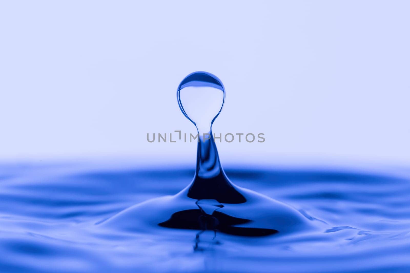 A pstudio image of a water drop in rippled water.