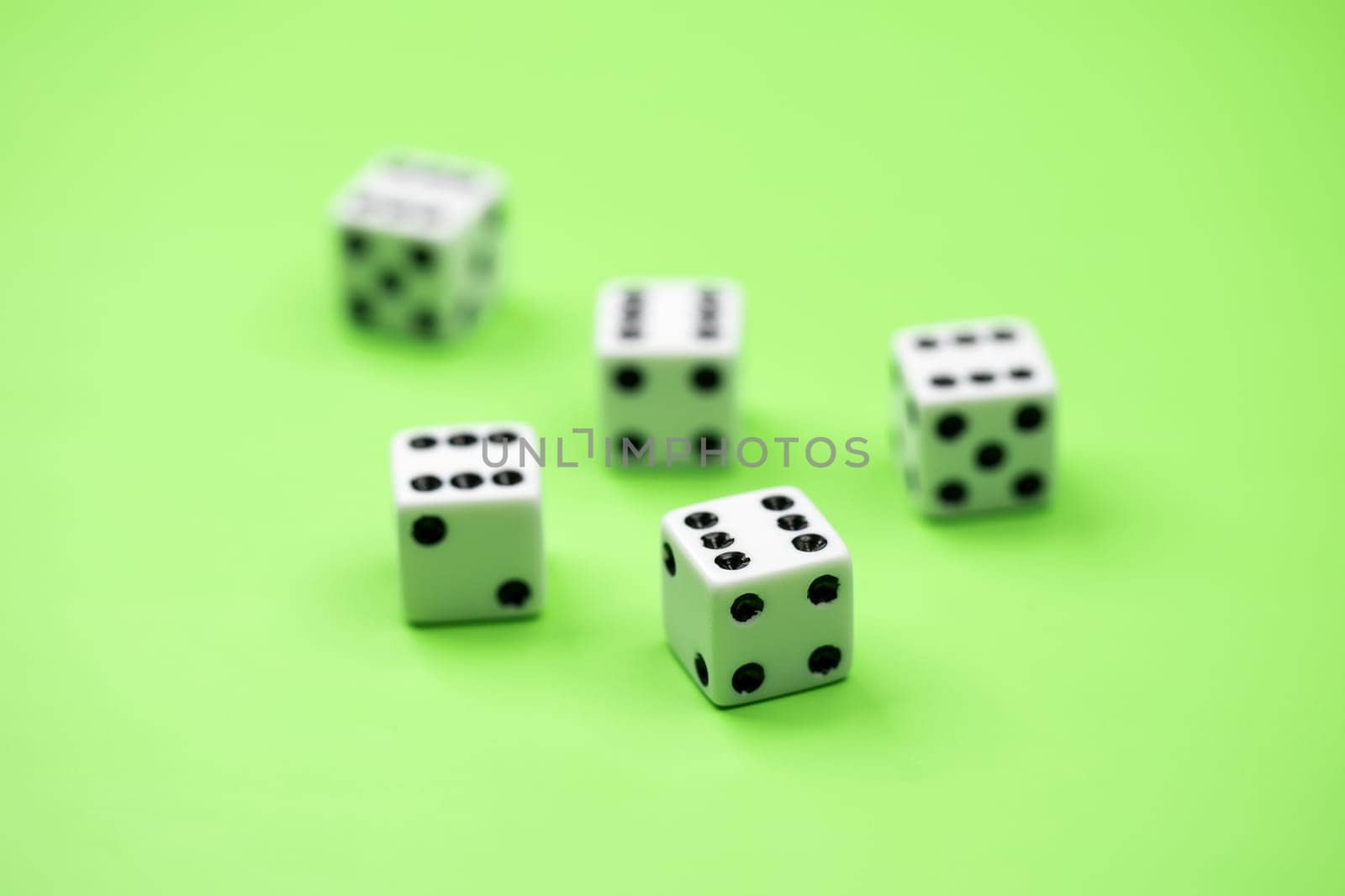 A conceptual photo of 5 dice on green with the number six showing.