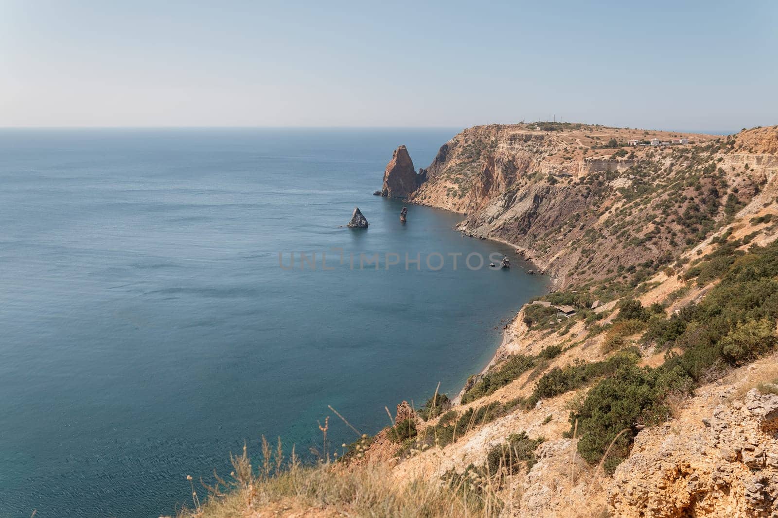 A beautiful ocean view with a rocky shoreline. The water is calm and the sky is clear