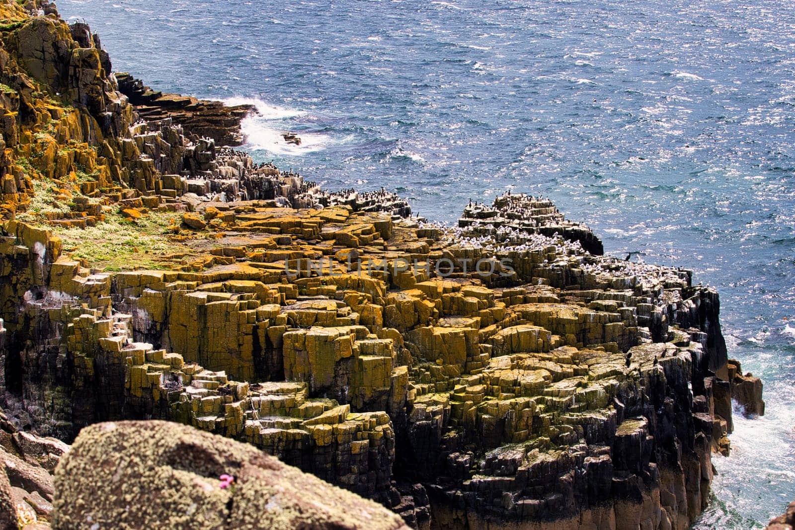 A sizable rock formation situated along the shoreline of a body of water, creating a striking natural landscape that attracts attention