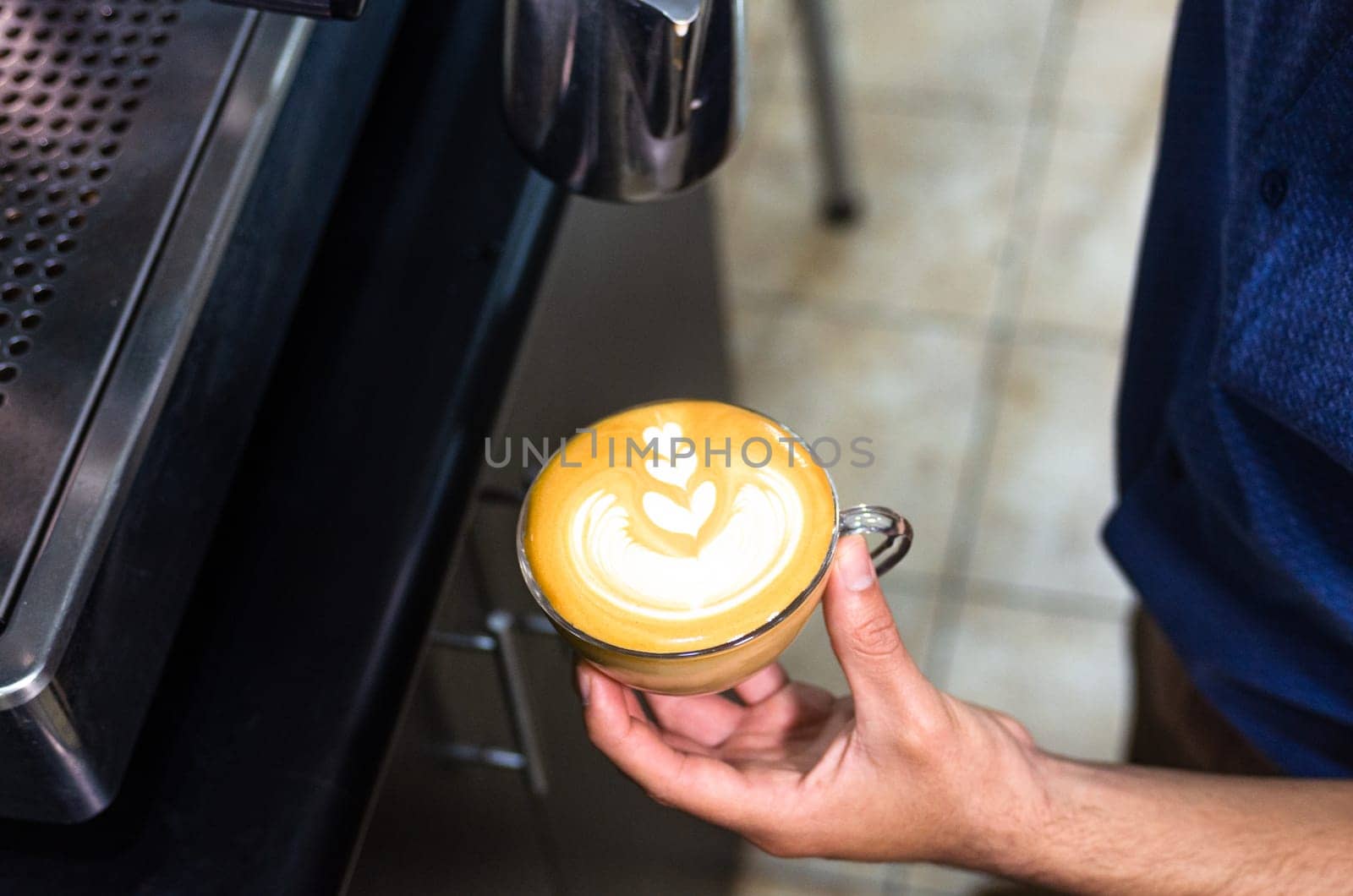 Hand of barista making latte or cappuccino coffee, pouring milk making latte art