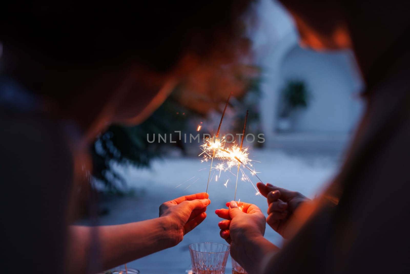 girls celebrating sparklers in hands close up in evening, holiday concept