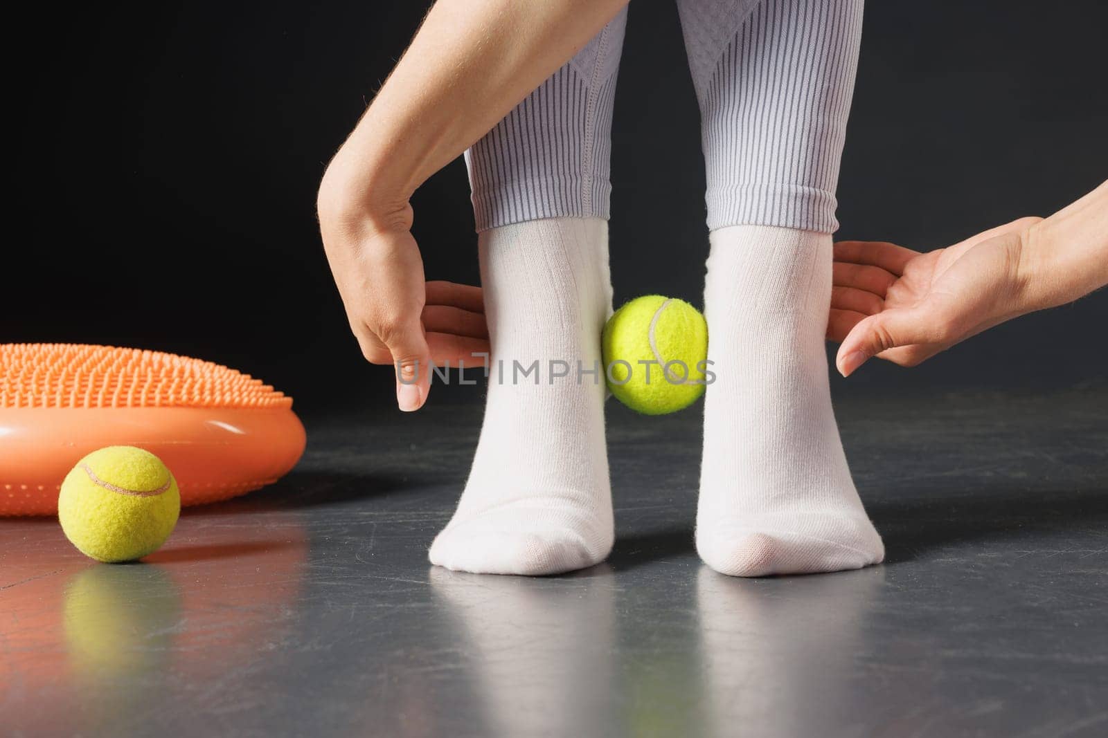 Strengthening the ankle joint with a tennis ball, a therapist is treating the legs, a close-up foot massage