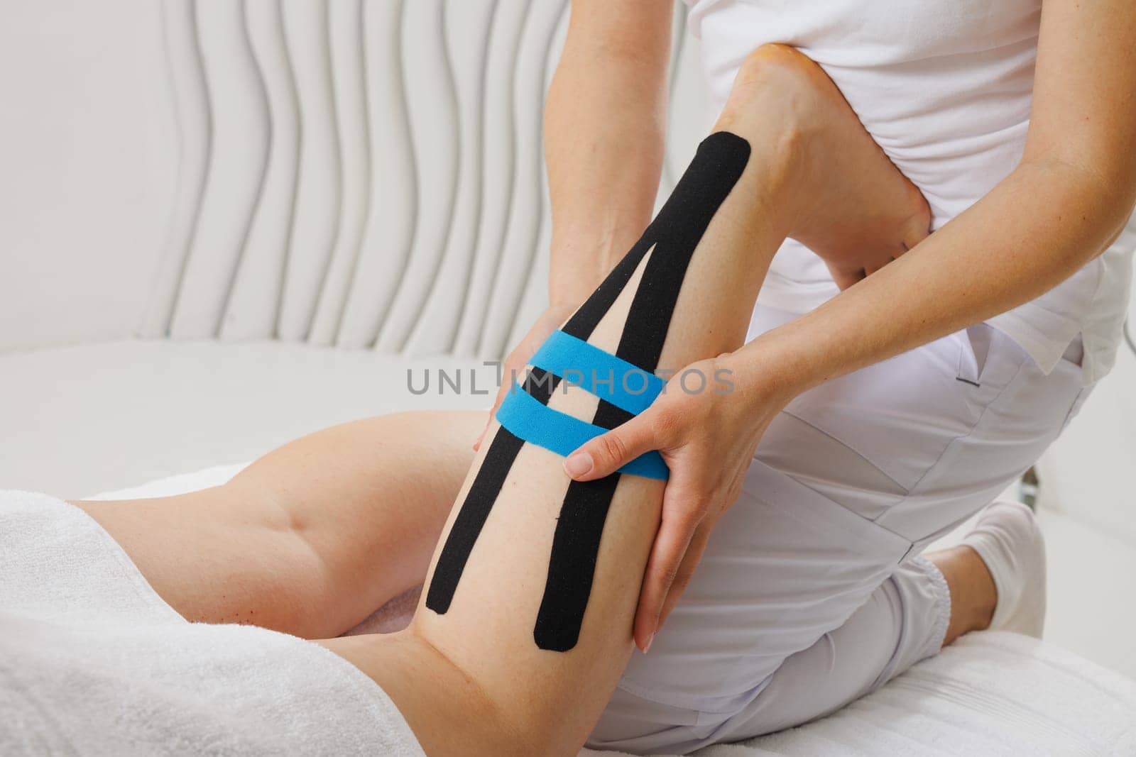 Kinesio taping of the lower extremities to prolong the massage effect close-up, the therapist applies tape to the patient's legs