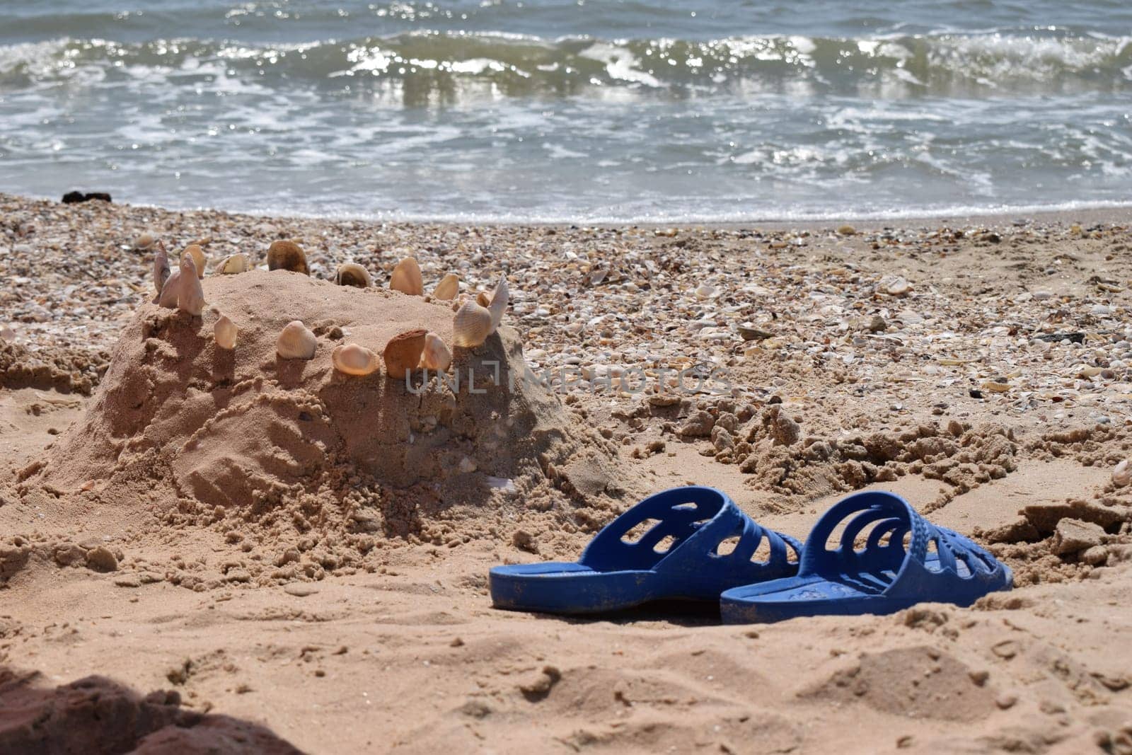 Beautiful beach. Blue Beach sandals on the sandy coast. Summer holiday and vacation concept. Pair of blue flip flops on sand beach