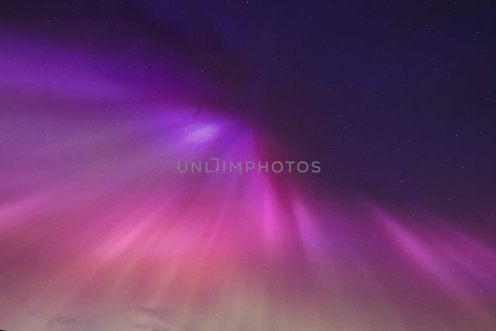 A mesmerizing image of the Aurora Borealis lighting up the night sky over North Berwick, Scotland. The vibrant purple and pink hues stretch across the dark sky, creating a breathtaking natural phenomenon. This rare sight captures the beauty and wonder of the Northern Lights in a coastal Scottish setting. Perfect for themes related to nature, astronomy, and landscape photography.
