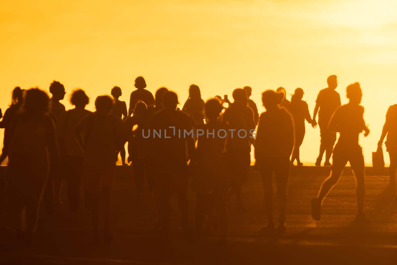 A crowd of young people at a bright sunset. Mid shot