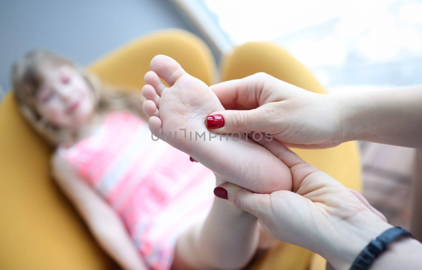 Podiatrist holding child leg in massage parlor closeup. Feet disease treatment concept