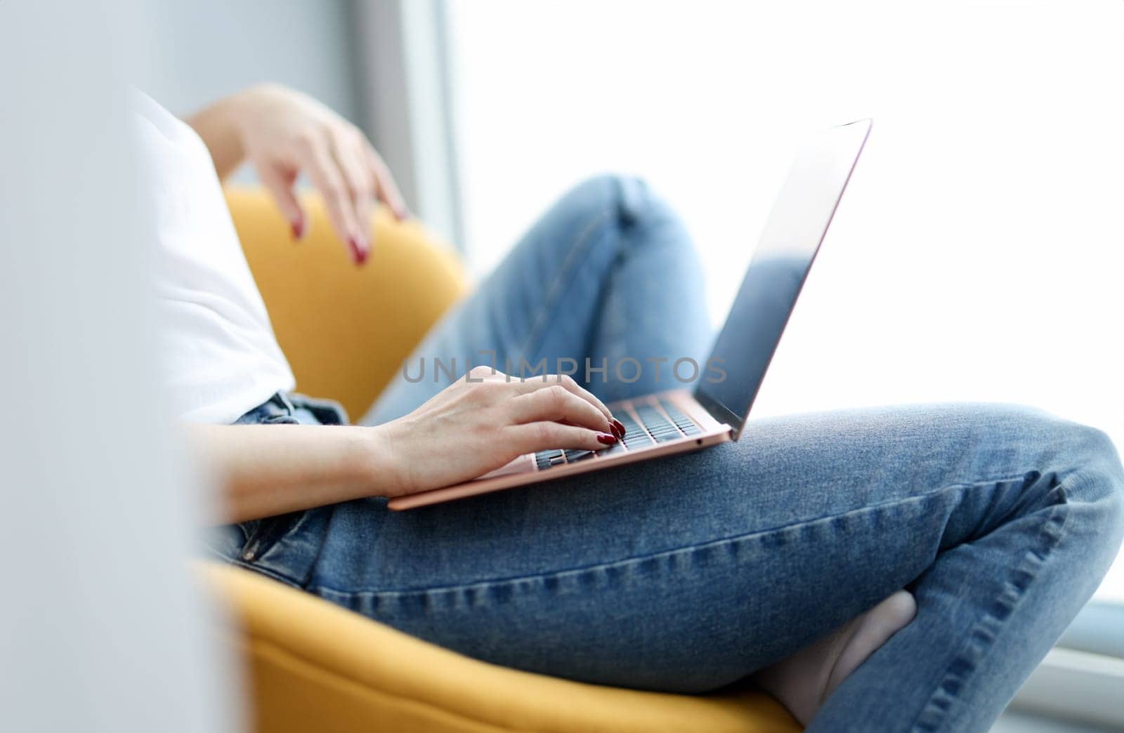 Woman sitting in chair with laptop on her lap closeup. Self isolation concept