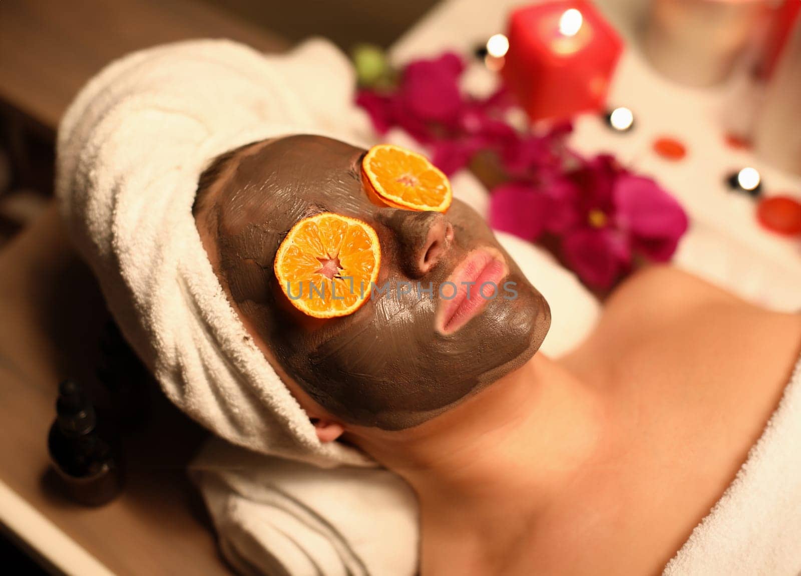 Portrait of woman with a rejuvenating face mask and orange slices on her eyes. Facial rejuvenation procedures concept