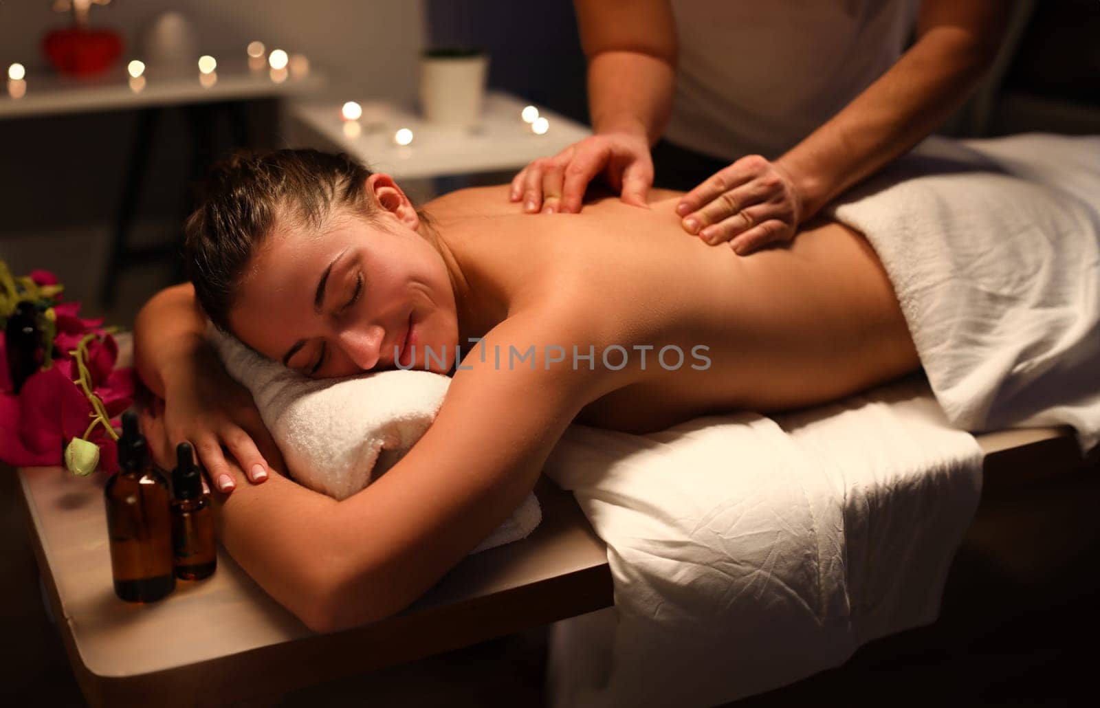 Smiling woman masseur doing back massage at spa center. Benefits of therapeutic massage for back and spine concept