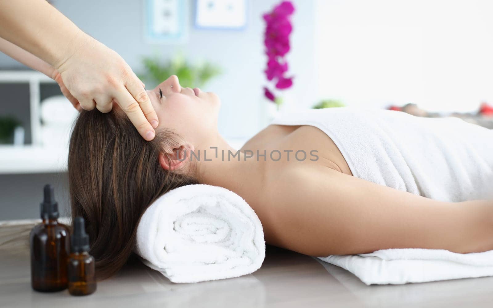 Young woman masseur makes relaxing head massage by kuprevich