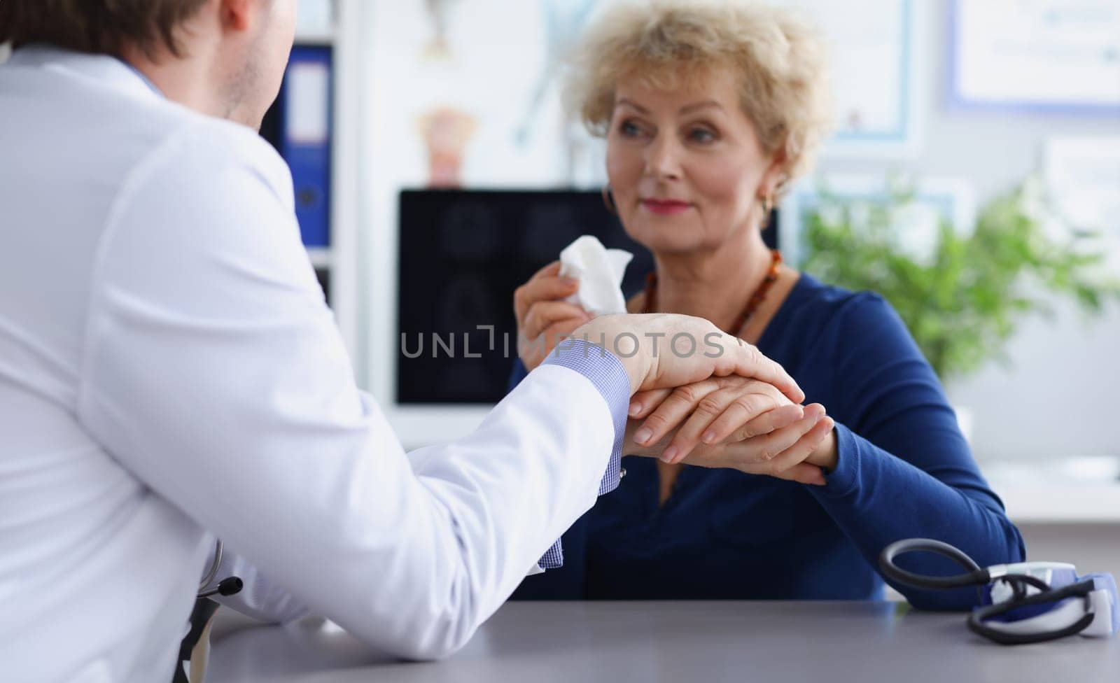 Doctor sympathetically holds hand of an elderly patient. Doctor and patient relationship concept