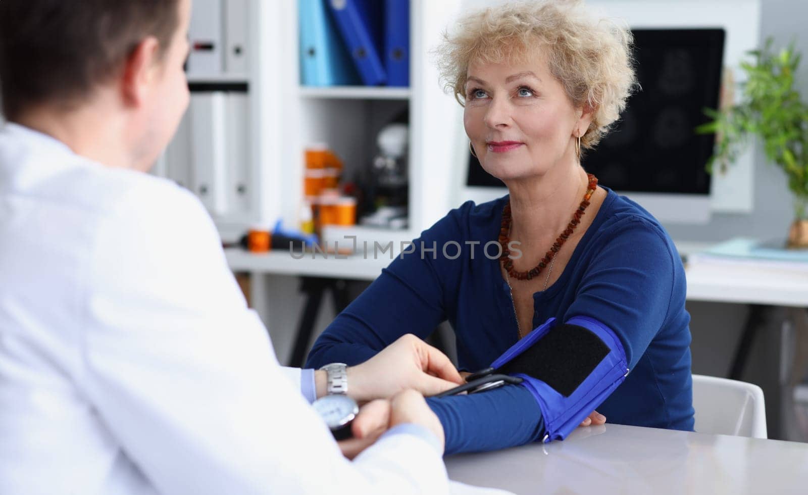Doctor measures blood pressure of an elderly woman in medical office. Blood pressure in the elderly concept