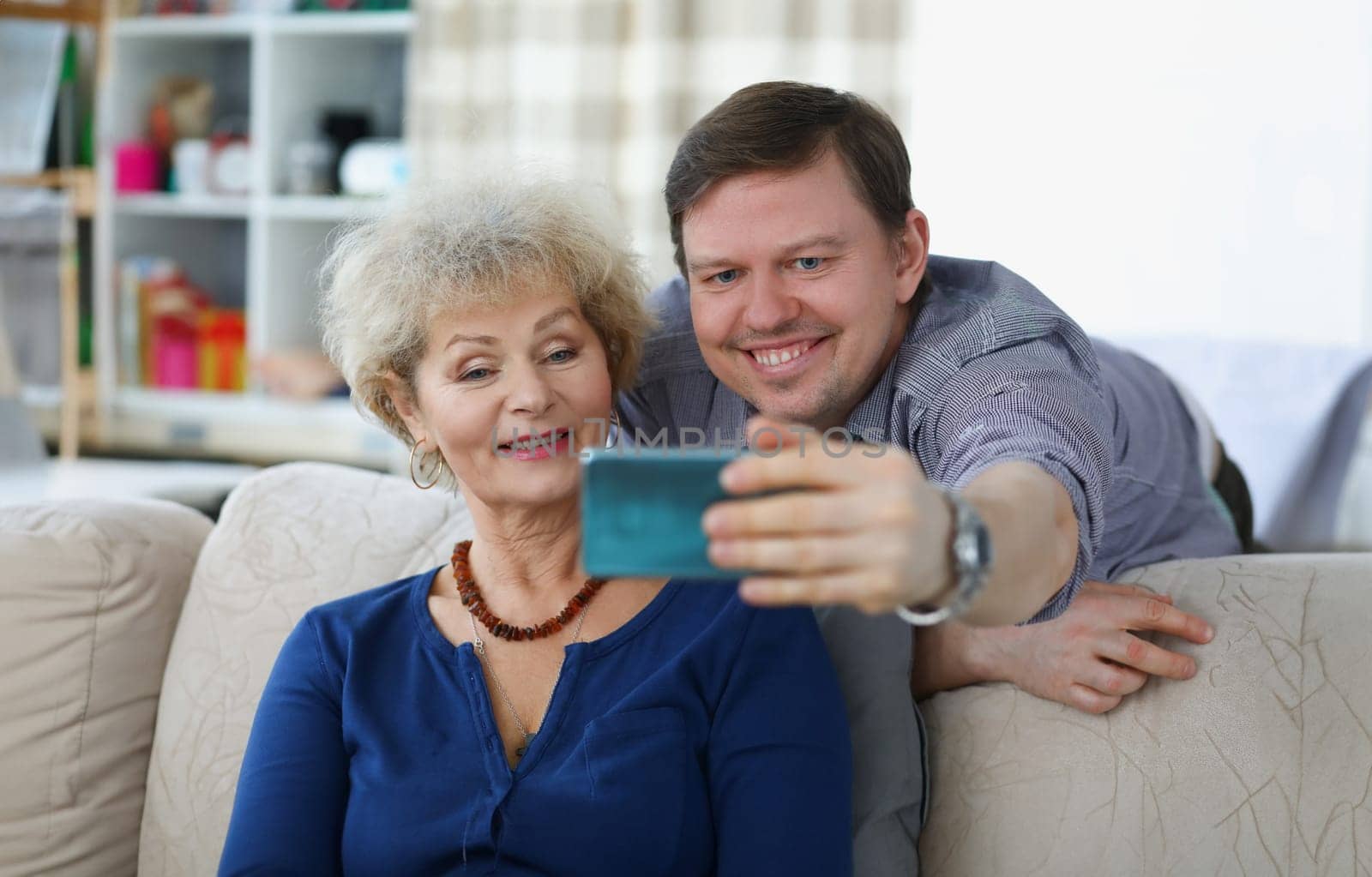 Young man takes selfie on smartphone with his mom by kuprevich