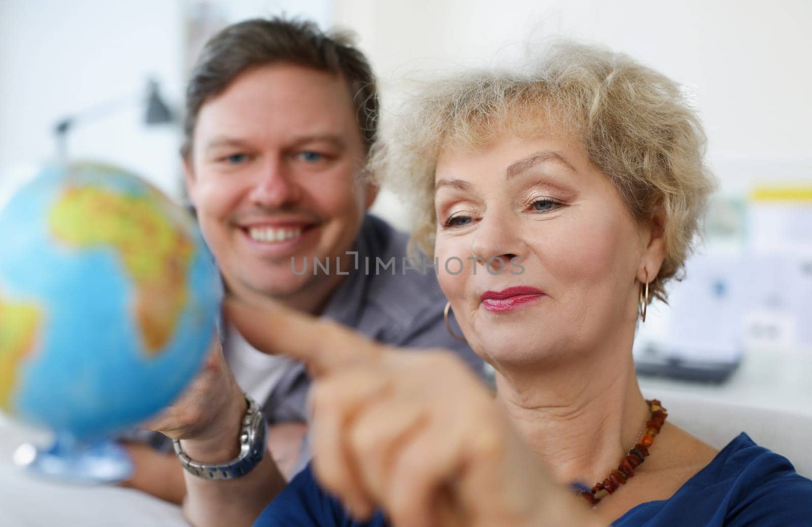 An elderly woman and young man looking at globe. Parents and children traveling together concept